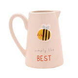 Cream stoneware jug with curved handle and spout, featuring an embossed smiling bee design and "simply the BEST" text in grey and red lettering, on a plain white background.