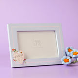 Blue wooden rectangular photo frame with stand, featuring a cream heart reading "FRIEND you are the loveliest of all" with floral details, shown against a lilac background.