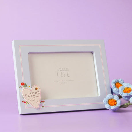 Blue wooden rectangular photo frame with stand, featuring a cream heart reading "FRIEND you are the loveliest of all" with floral details, shown against a lilac background.