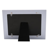 Back view of the Friend Heart Floral wooden photo frame showing a white frame, black backing, fold-out stand, and metal hanging tabs on a plain background.
