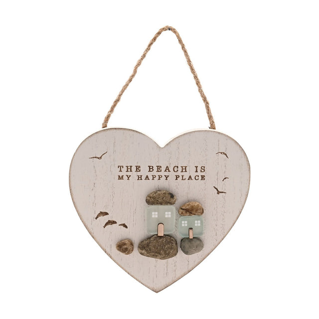 White heart-shaped wall plaque with jute cord, reading THE BEACH IS MY HAPPY PLACE above frosted sea glass cottages on pebble bases with gulls in flight, white background.