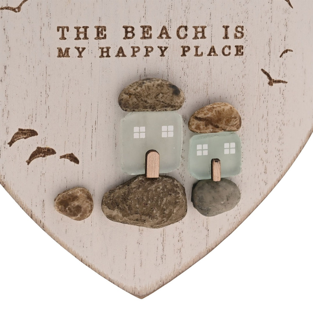 White heart-shaped wall plaque with "The Beach Is My Happy Place" text, featuring frosted green glass cottages among pebble shapes and engraved flying gulls.
