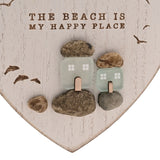 White heart-shaped wall plaque with "The Beach Is My Happy Place" text, featuring frosted green glass cottages among pebble shapes and engraved flying gulls.