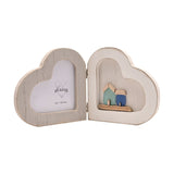 White wooden folding double heart photo frame with a heart-shaped photo window on one side and a small seaside scene of two wooden houses on the other.