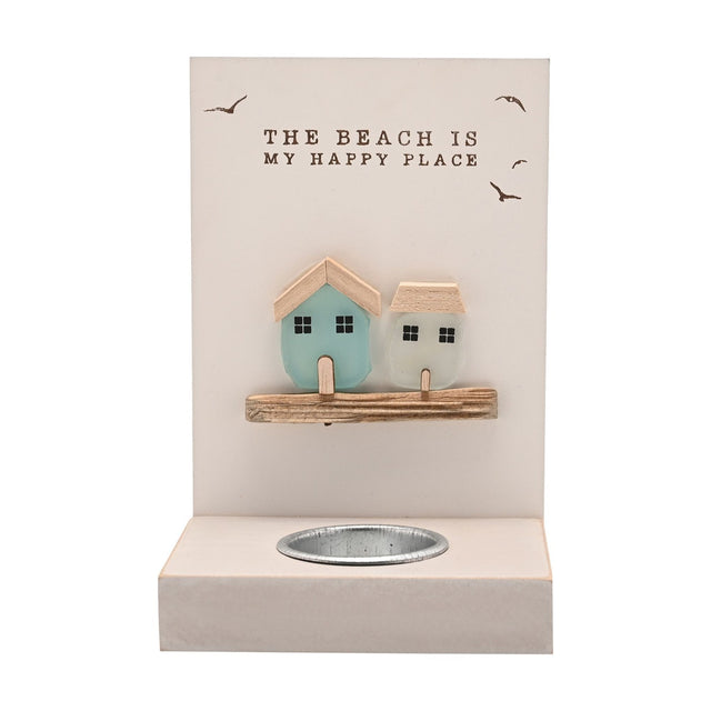 Cream tea light candle holder with sea glass houses in aqua and frosted white, "THE BEACH IS MY HAPPY PLACE" text and bird motifs on a wood plaque above a metal tea light cup, plain background.