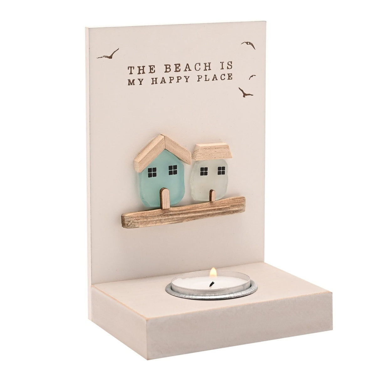 Cream wooden tea light candle holder with "The Beach Is My Happy Place" text, two sea glass house ornaments on a ledge, lit tea light below, on a plain white background.