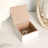 Square white wooden trinket box with hinged lid open, showing a plain interior holding a set of keys on a ring, styled with coastal décor.