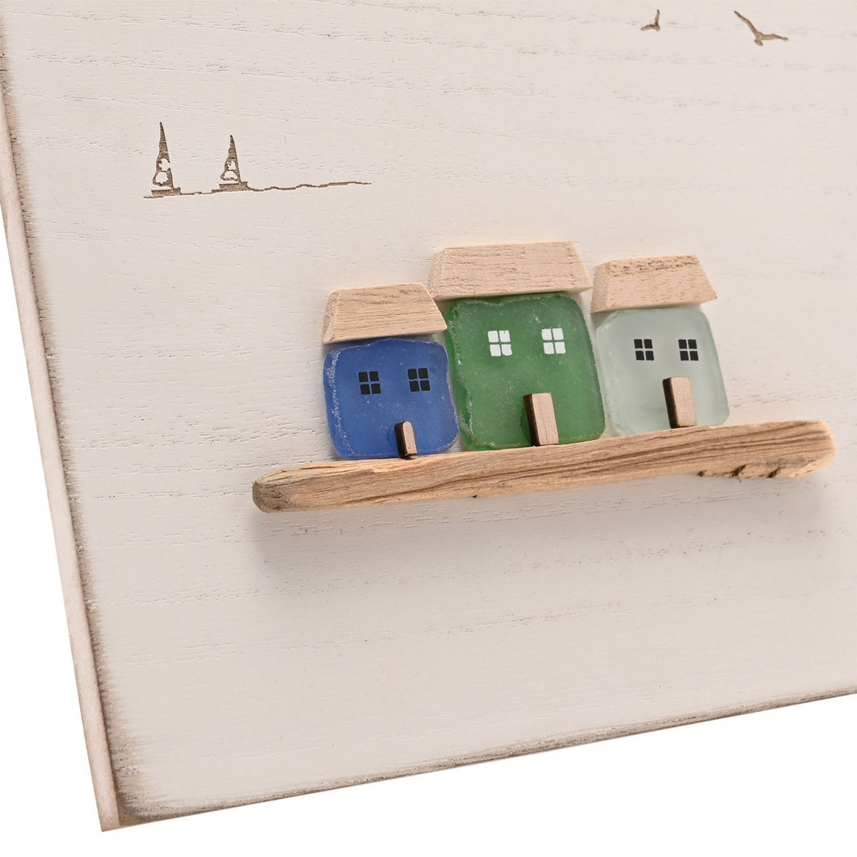 White square wall plaque with three glass cottage houses in cobalt blue, green and pale aqua on a wooden ledge, with engraved gulls and sailboats above.