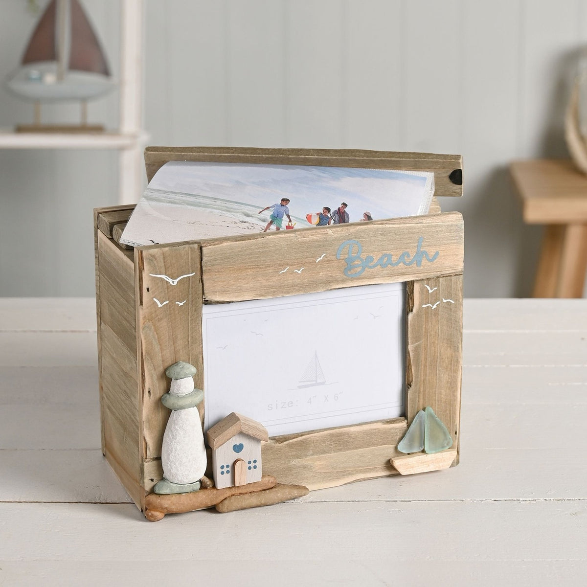 Beach Driftwood Photo Trinket Box in natural wood, lid open with photo insert, featuring a 4"x6" picture window, pebble lighthouse, tiny house with blue heart, and sea glass-sailed boat.