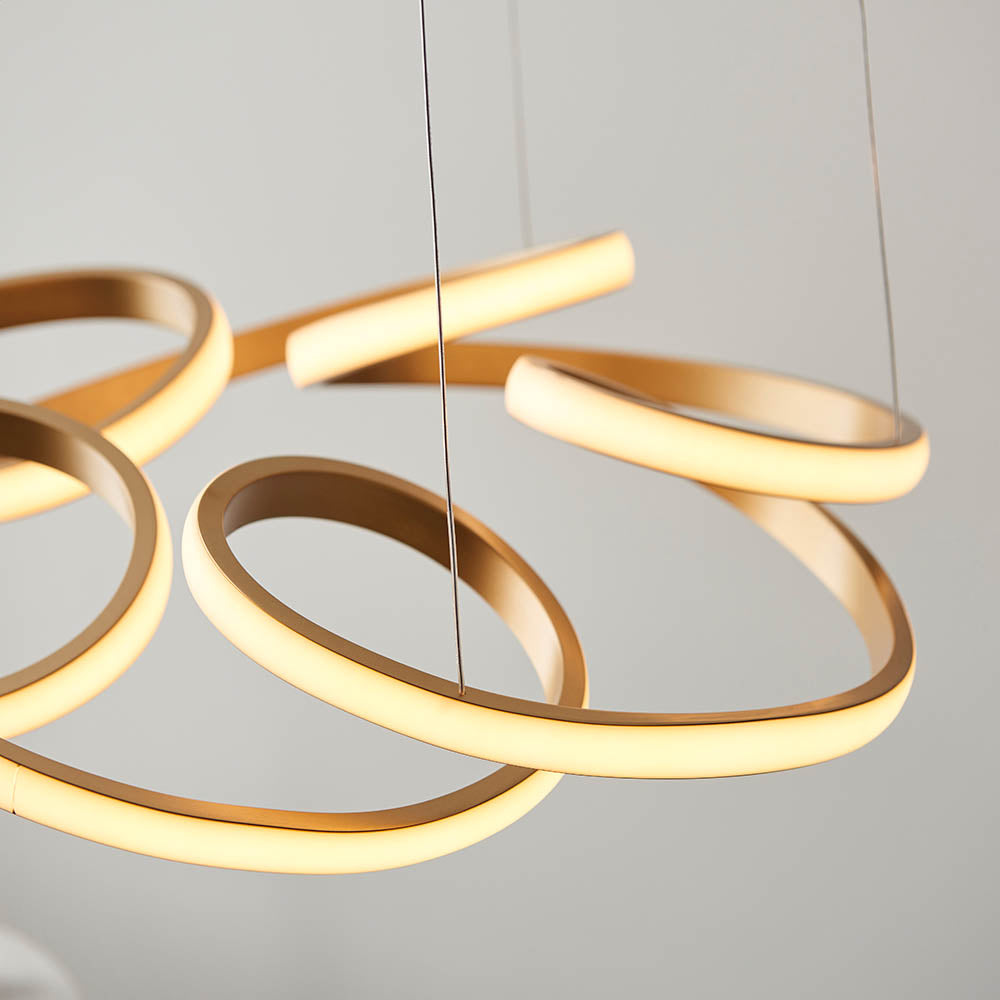 Close-up of the Lighting No.1 Tolmere Multi Spiral LED Pendant in satin gold, showing the continuous looped metal ribbon glowing warm white.