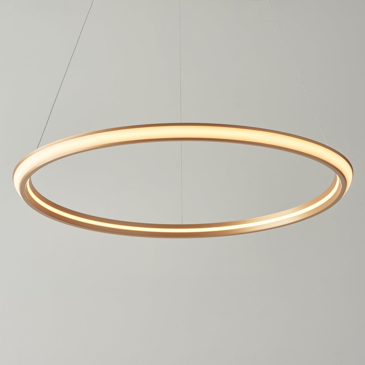 Ashenhurst LED Ring Pendant by Lighting No.1 in satin gold, a slim illuminated circular ring suspended by thin cables against a light grey background.