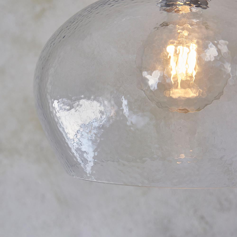 Close-up of Lighting No.1 Draywick Hammered Medium Pendant in clear dimpled glass with bright nickel fitting and lit E27 bulb inside.