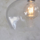 Close-up of Lighting No.1 Draywick Hammered Medium Pendant in clear dimpled glass with bright nickel fitting and lit E27 bulb inside.