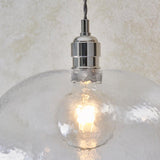 Close-up of the Lighting No.1 Draywick Hammered Medium Pendant in clear glass with bright nickel fitting, glowing E27 bulb visible through the dimpled shade.