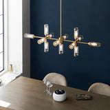 Gorsewell Ribbed Linear 13 Light Pendant in frosted satin brass, illuminated over a wooden dining table against a deep navy wall.