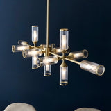 Gorsewell Ribbed Linear 13 Light Pendant in satin brass with ribbed frosted glass shades on a sputnik-style bar, shown against a dark blue background.