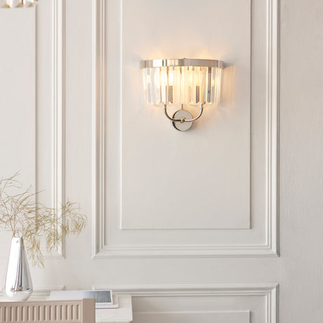 Calverdale Cut 2 Light Wall Light in bright nickel with faceted cut glass shades, illuminated on a panelled off-white wall above a console.