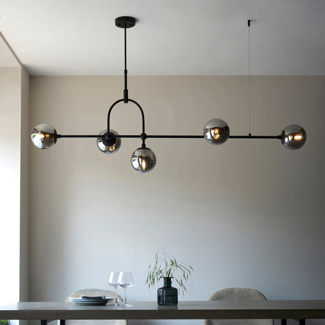 Lighting No.1 Haldmere linear 5-light pendant with smoked grey glass spheres on a matt black adjustable bar, shown above a dining table.