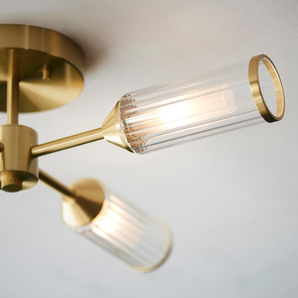 Close-up of Lighting No.1 Gorsewell Ribbed Semi-flush ceiling light showing satin brass arms and ribbed frosted glass shades with a lit G9 bulb.