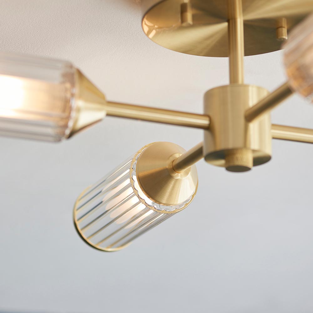 Close-up of Lighting No.1 Gorsewell Ribbed Semi-flush 4 Light ceiling fitting, showing satin brass arms and a ribbed frosted glass cylinder shade.