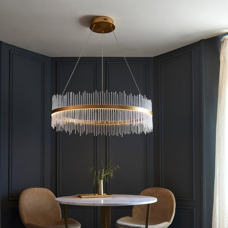 Rookhurst Rod Grand Pendant in gold by Lighting No.1, a wide round chandelier of clear glass rods above a marble dining table in a navy panelled room.