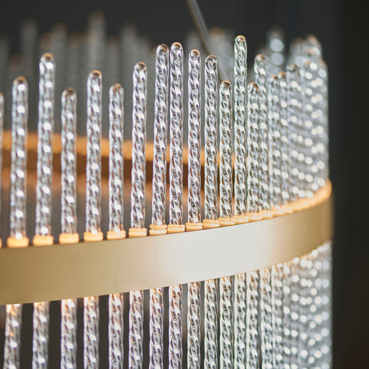 Close-up of the Lighting No.1 Rookhurst Rod Grand Pendant showing twisted clear glass rods set upright in a brushed gold circular frame.