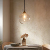 Yarnwell Bubble Pendant in clear bubbled glass with a domed globe shade and metal fitting, hung above a dining table set with dried flowers.