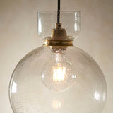 Yarnwell Bubble Pendant in clear bubbled glass with brass fitting and lit E27 filament bulb, suspended from a black cord by Lighting No.1.