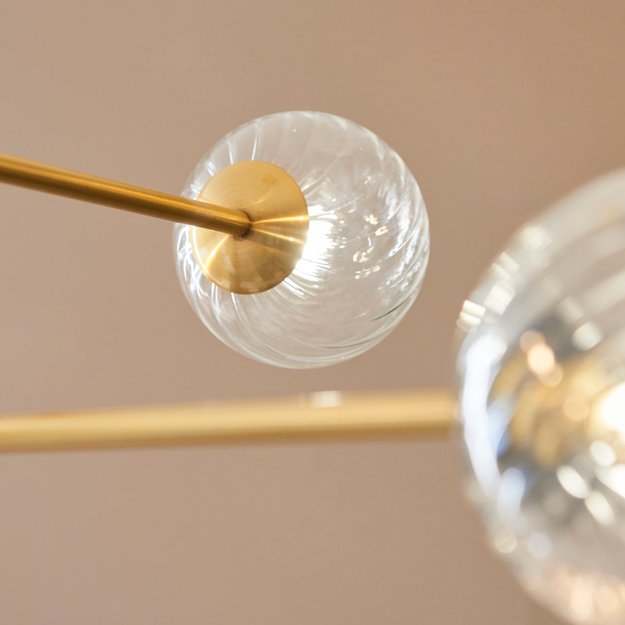 Close-up of the Lighting No.1 Mossgrove Twisted 6 Light Pendant showing brushed aged brass arms holding twisted clear glass globe shades.