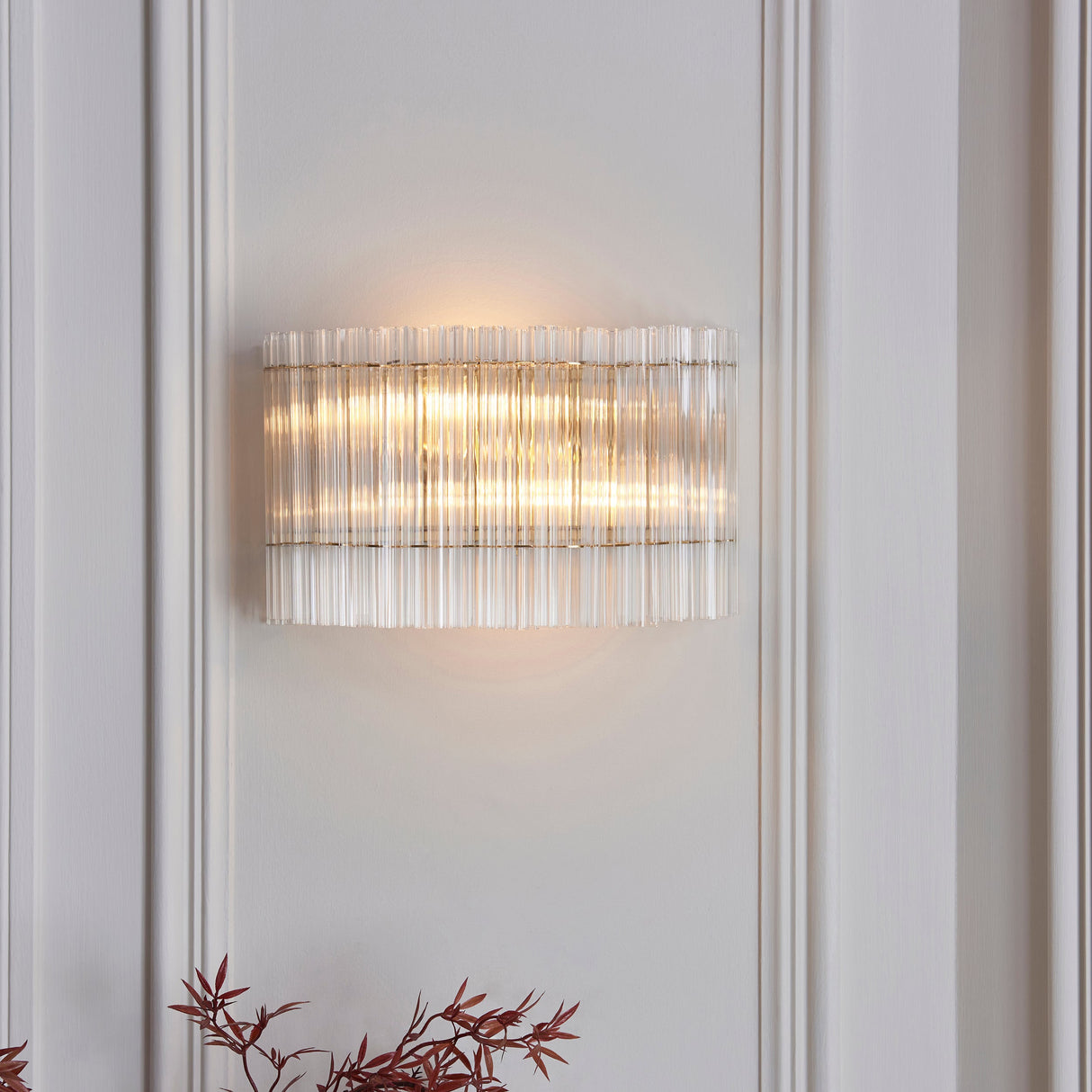 Nettlecote 2 light wall light from Lighting No.1 with clear ribbed glass shades in a brushed aged brass frame, mounted on a panelled wall.