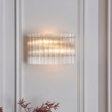 Nettlecote 2 light wall light from Lighting No.1 with clear ribbed glass shades in a brushed aged brass frame, mounted on a panelled wall.