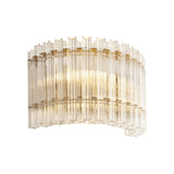 Nettlecote 2 light wall light by Lighting No.1 with clear ridged glass shades in a curved brushed aged brass frame, illuminated on a white background.