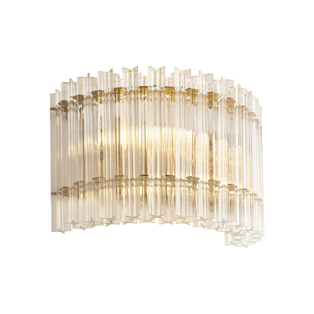 Nettlecote 2 light wall light by Lighting No.1 with clear ridged glass shades in a curved brushed aged brass frame, illuminated on a white background.