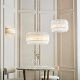 Lighting No.1 Nettlecote 2 light wall light in brushed aged brass with clear glass shades, shown beside matching pendants above a marble bistro table.
