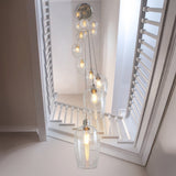 Quilbrook Cascade 13 light pendant from Lighting No.1 with clear glass globes spiralling from a bright nickel plate down a white stairwell.