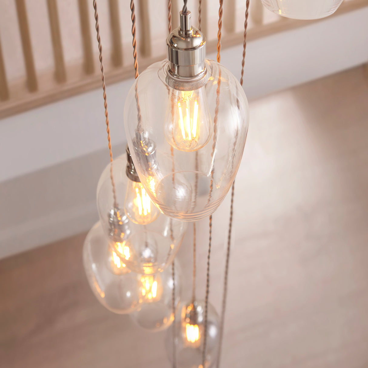 Close-up of the Lighting No.1 Quilbrook Cascade 13 light pendant showing clear glass globes with filament LED bulbs suspended on bright nickel fittings.