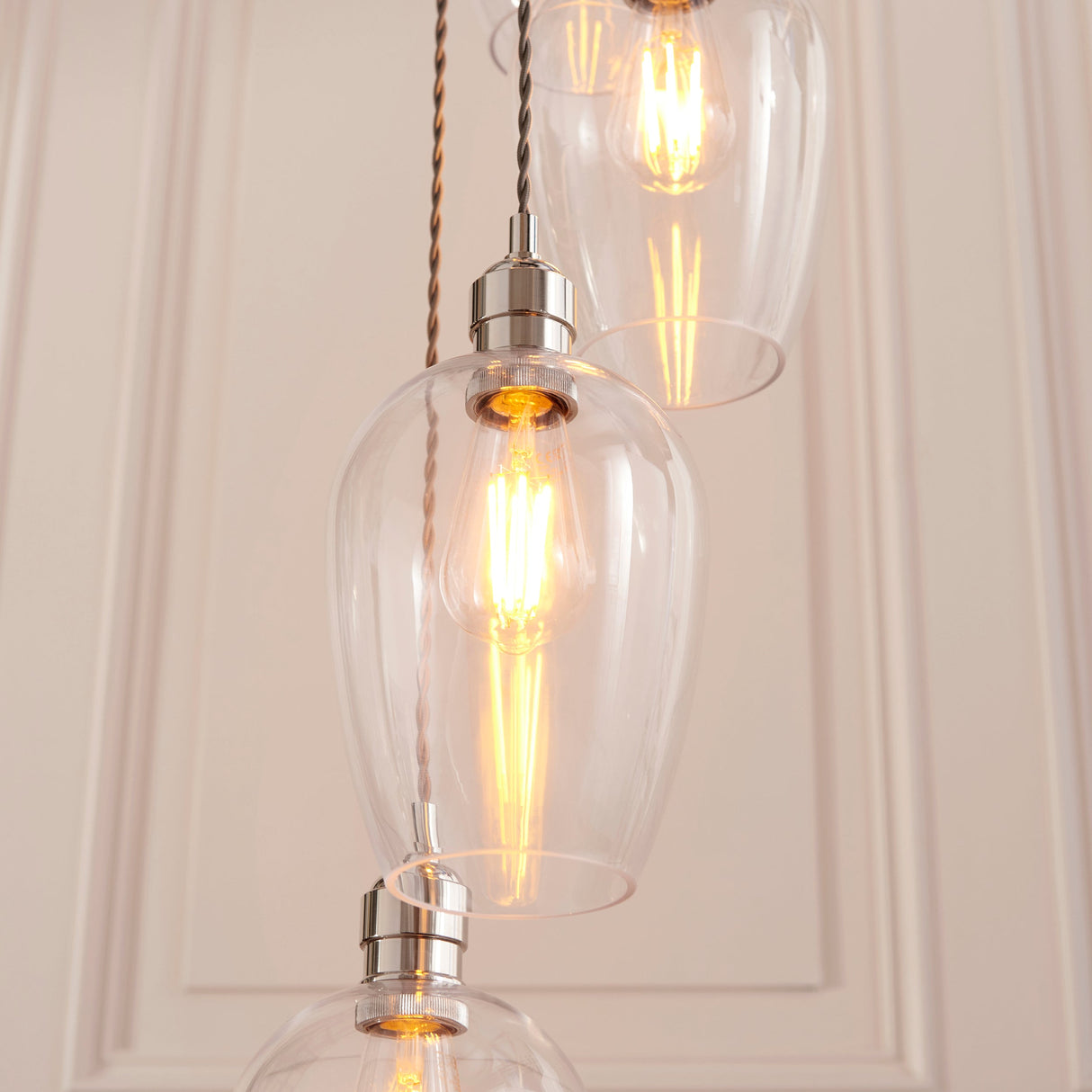 Quilbrook Cascade pendant by Lighting No.1 with clear glass globe shades and bright nickel fittings suspended at staggered heights with lit filament bulbs.