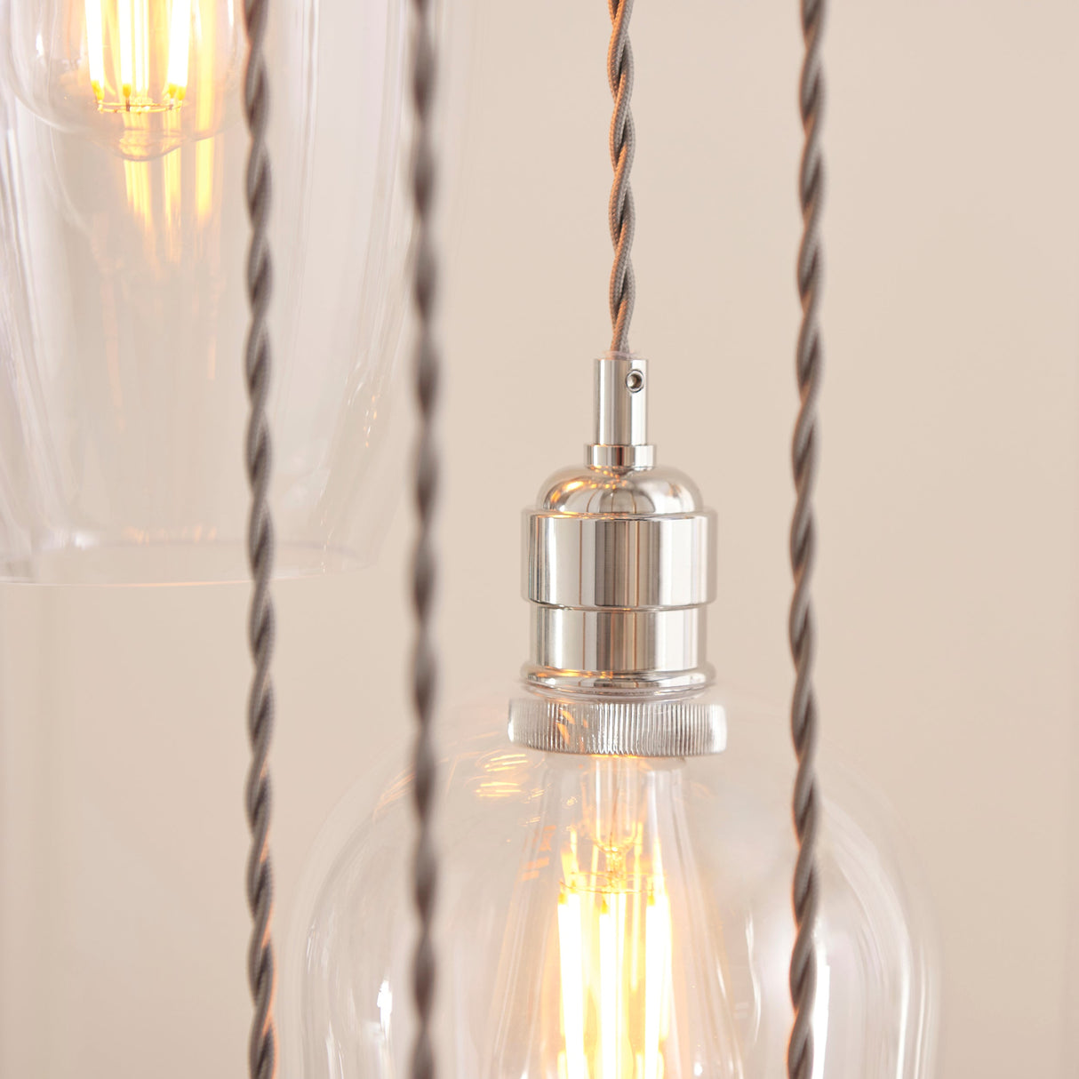 Close-up of the Lighting No.1 Quilbrook Cascade pendant showing a nickel E27 holder, twisted grey cables, and clear glass globes with lit filament bulbs.