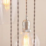 Close-up of the Lighting No.1 Quilbrook Cascade pendant showing a nickel E27 holder, twisted grey cables, and clear glass globes with lit filament bulbs.