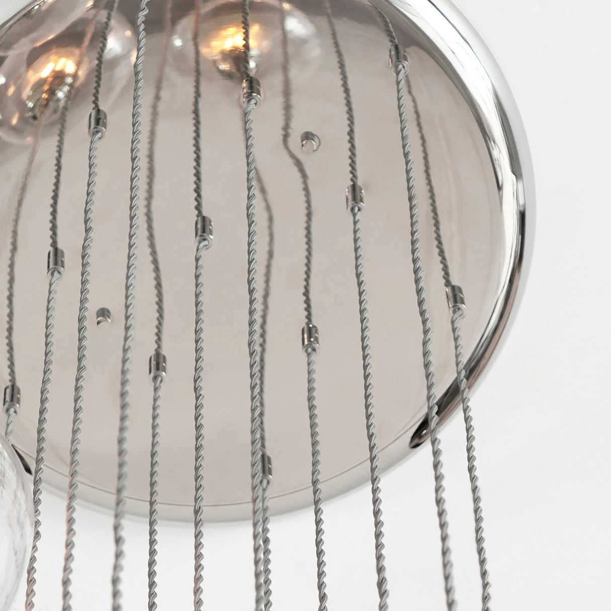 Close-up of the Lighting No.1 Quilbrook Cascade 13 light pendant showing the bright nickel ceiling plate with suspension cables and illuminated bulbs.