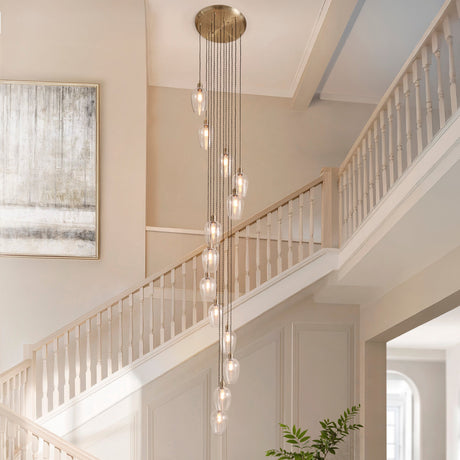Quilbrook Cascade 13 light pendant from Lighting No.1 in antique brass with clear glass globes staggered down a stairwell beside a painting and banister.