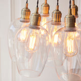 Close-up of the Lighting No.1 Quilbrook Cluster 7 Light Pendant in antique brass, showing clear glass globes and warm filament E27 bulbs.