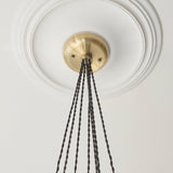Close-up of the Quilbrook Cluster 7 Light Pendant ceiling plate in antique brass, mounted on a circular ceiling rose with twisted black cables descending.