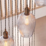 Close-up of Lighting No.1 Fennhollow Ribbed Cascade pendant showing ribbed clear glass globes on antique brass fittings with twisted flex cables in a stairwell.