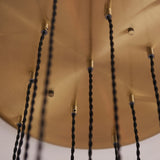 Close-up of the Fennhollow Ribbed Cascade 13 Light Pendant by Lighting No.1, showing the antique brass ceiling plate with black twisted cables.