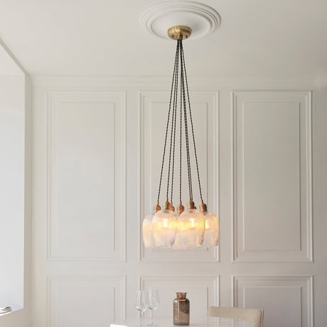 Fennhollow Ribbed Cluster 7 Light Pendant in antique brass with clear ribbed glass globes, hung from twisted black cables in a panelled dining room.