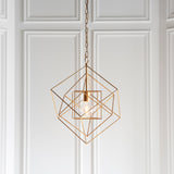 Padgrove Medium Angular Framed Single Pendant in gold leaf by Lighting No.1, hung on a chain against white panelled wall with exposed E27 bulb.