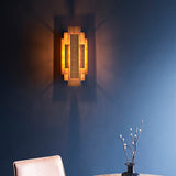Dunmoor Rectangular Panel 2 Light Wall Light in gold by Lighting No.1, lit on a deep blue corner wall above a velvet chair and vase of pussy willow.