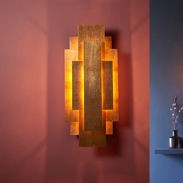 Dunmoor Rectangular Panel 2 Light Wall Light in gold by Lighting No.1, layered metal panels casting warm glow on a deep red wall.