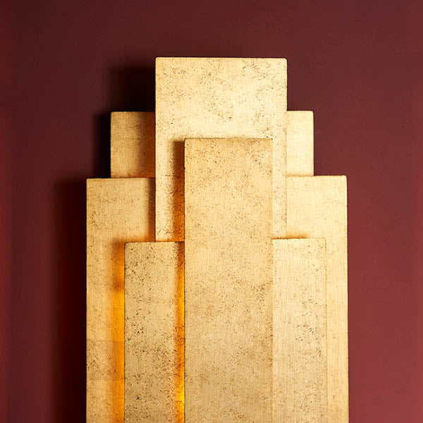 Dunmoor 2 light wall light from Lighting No.1 in gold, showing stacked rectangular metal panels in a tiered art deco layout against a deep red wall.